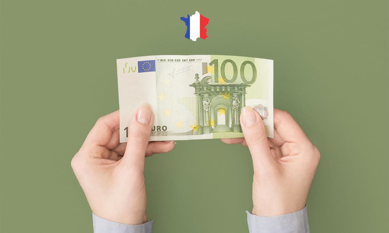 Mains qui tiennent un billet de banque de 100 euros avec une image de la France