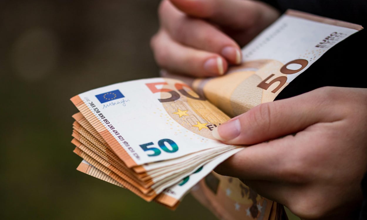 Mains comptant une liasse de billets de 50 euros