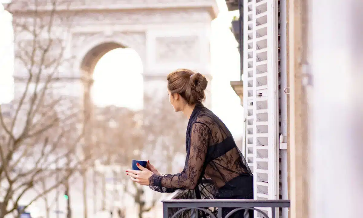 Femme sur le balcon d'un appartement parisien devant l'Arc de Triomphe à Paris