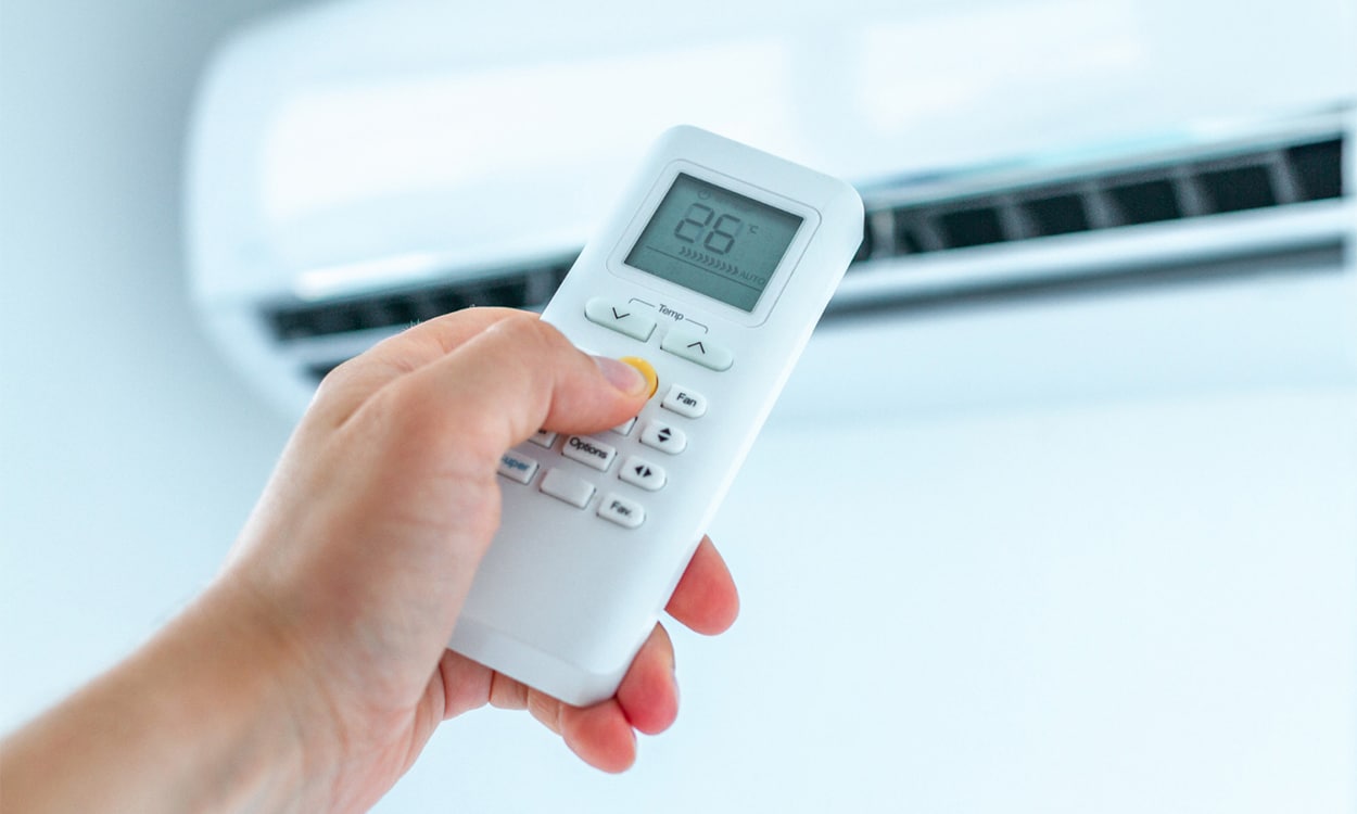 Utilisateur qui règle la température de sa climatisation réversible avec une télécommande