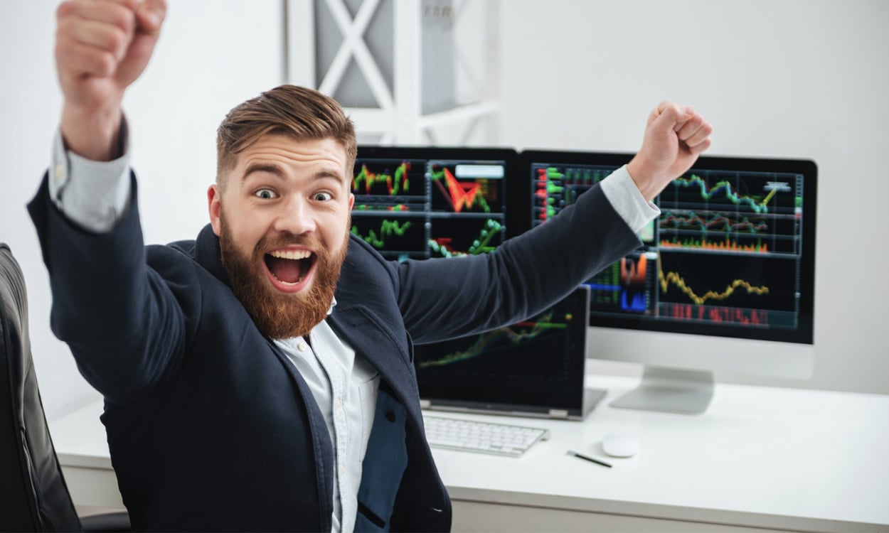 Investisseur triomphant devant des écrans d'analyse boursière