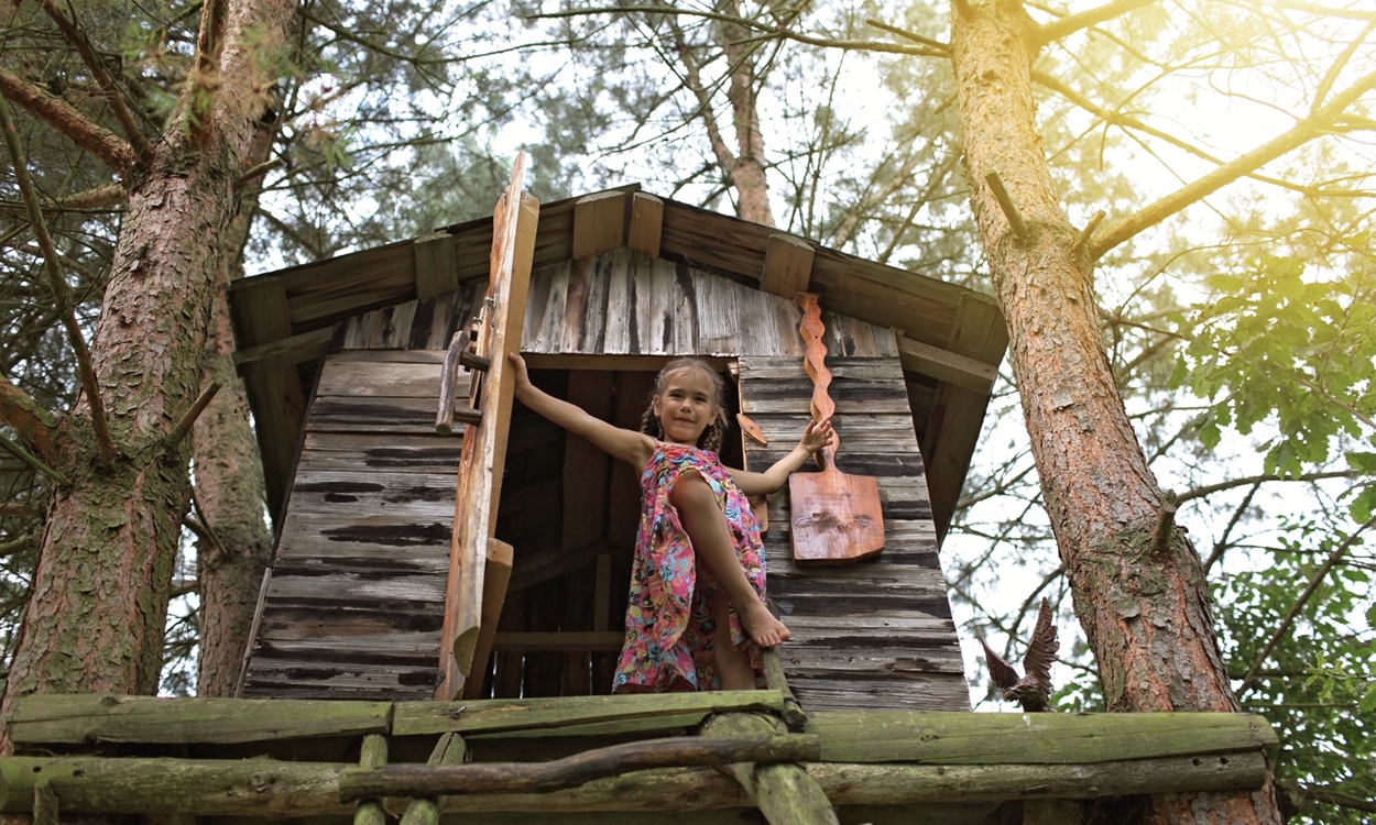 Petite fille devant l'entrée d'une cabane dans un arbre