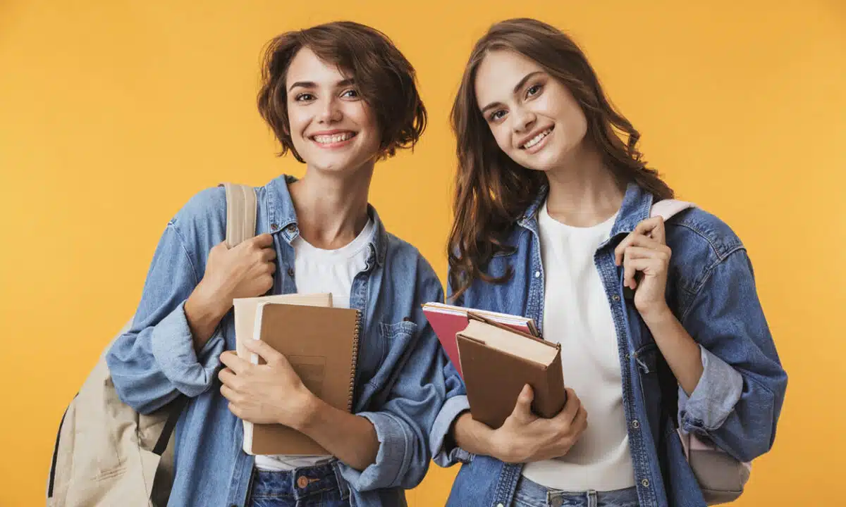 Deux belles étudiantes qui tiennent des livres et leur sac de classe avec le sourire