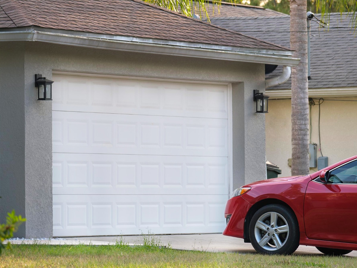 Voiture rouge devant la porte de garage d'une maison.
