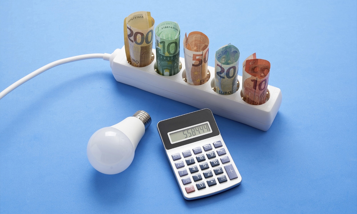 Prise électrique avec des billets de banque, une ampoule et une calculatrice