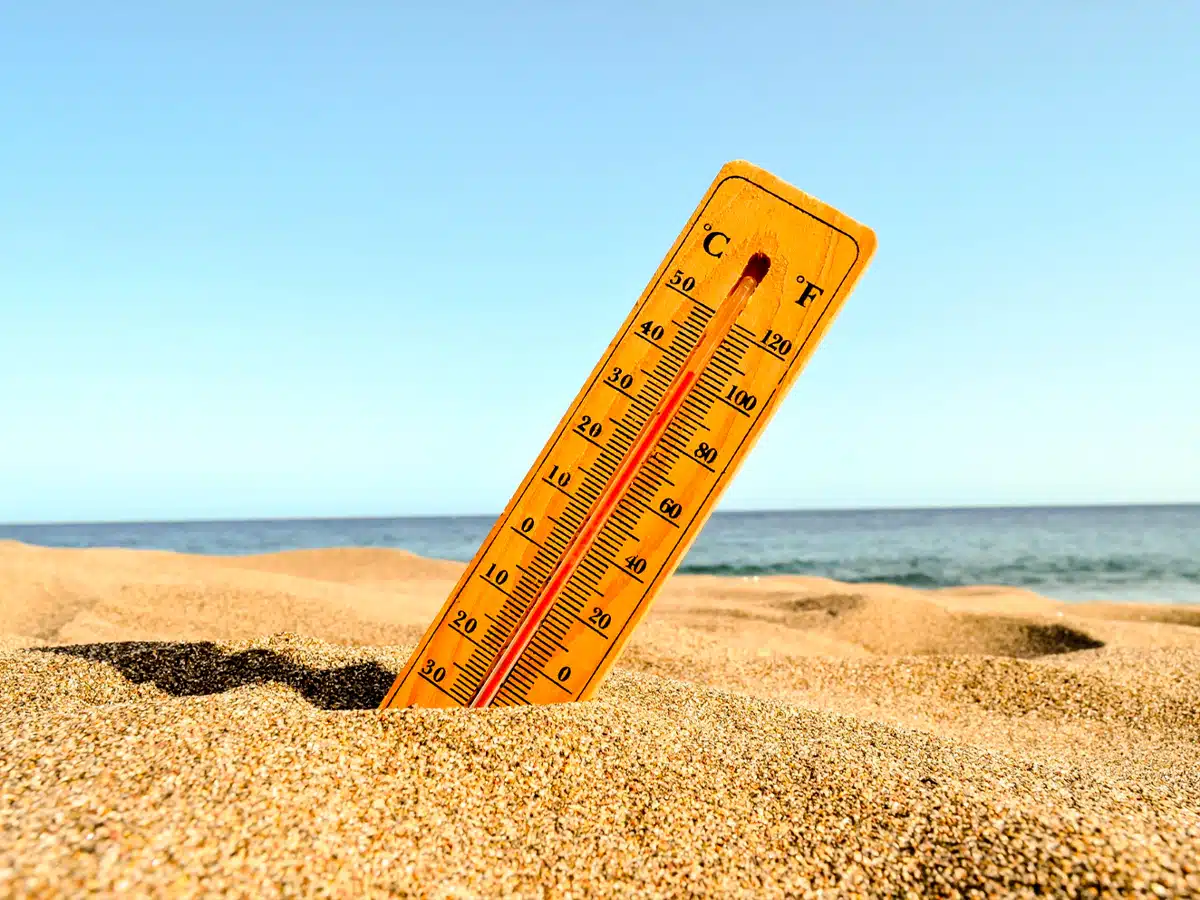 Thermomètre planté dans le sable qui affiche une température de 40°C