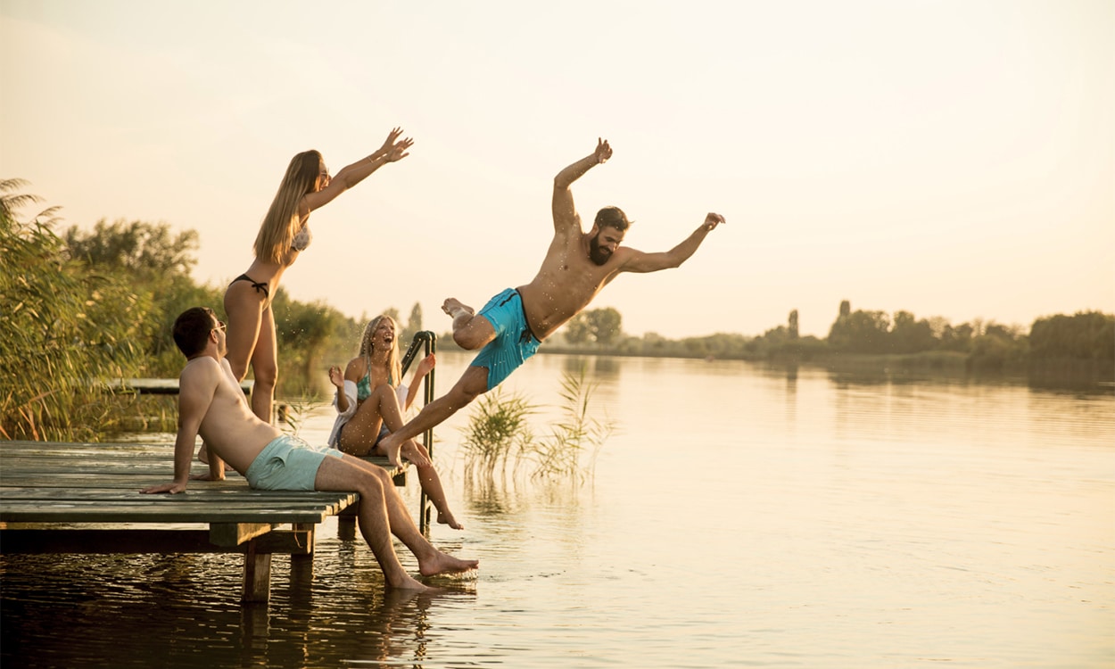 Groupe d'amis sur le ponton d'un lac pour se baigner