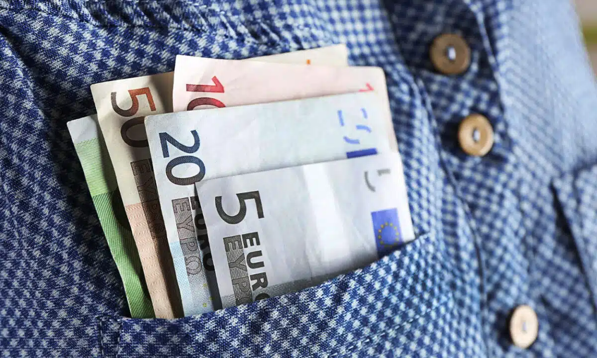 Liasses de billets euros dans la poche d'une chemise bleue à carreaux