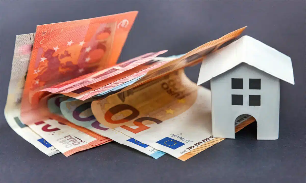 Une maison a coté d'une liasse de billets de banque en euro