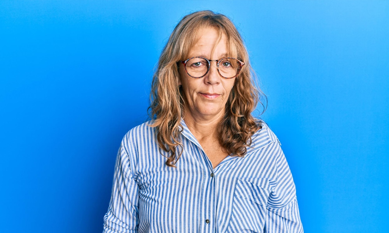 Femme 50 ans à lunettes en chemise sur fond bleu