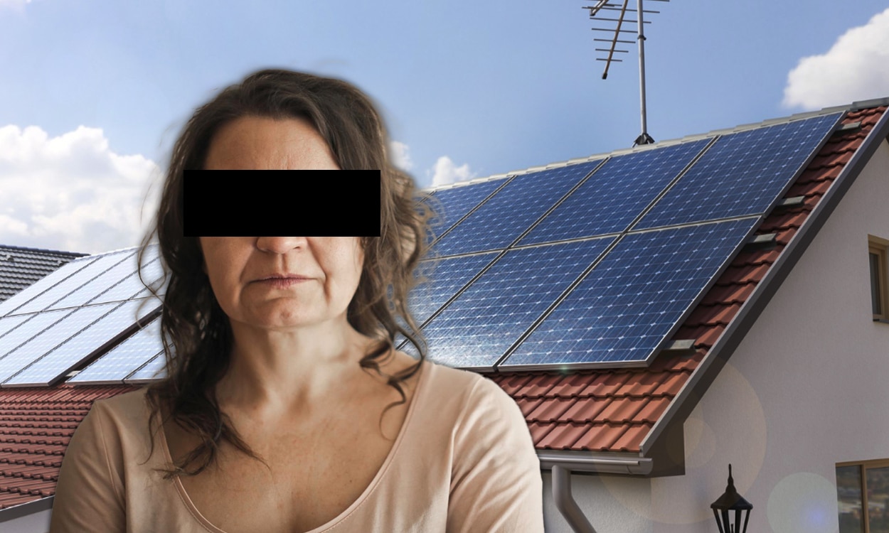 Femme anonyme devant une installation solaire sur le toit d'une maison individuelle