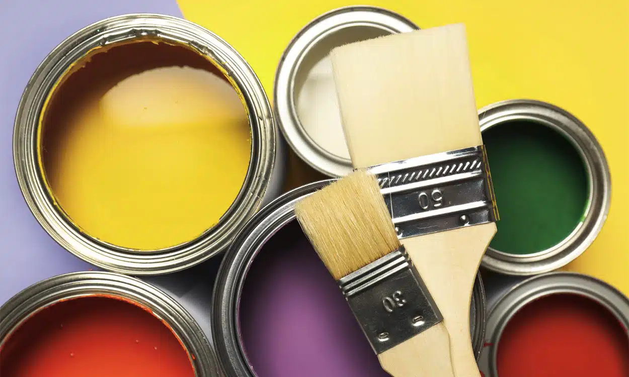 Pots de pentures de couleur ouverts avec des pinceaux posés dessus