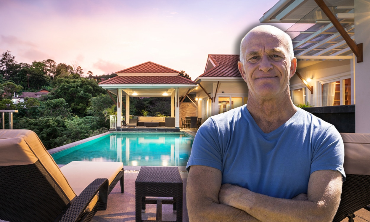 Un propriétaire qui pose devant sa belle maison avec piscine