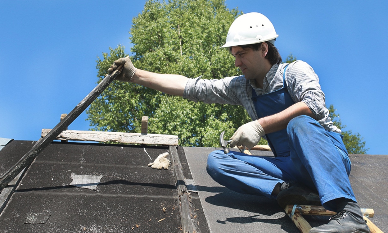 Charpentier sur un toit en train de faire des réparations