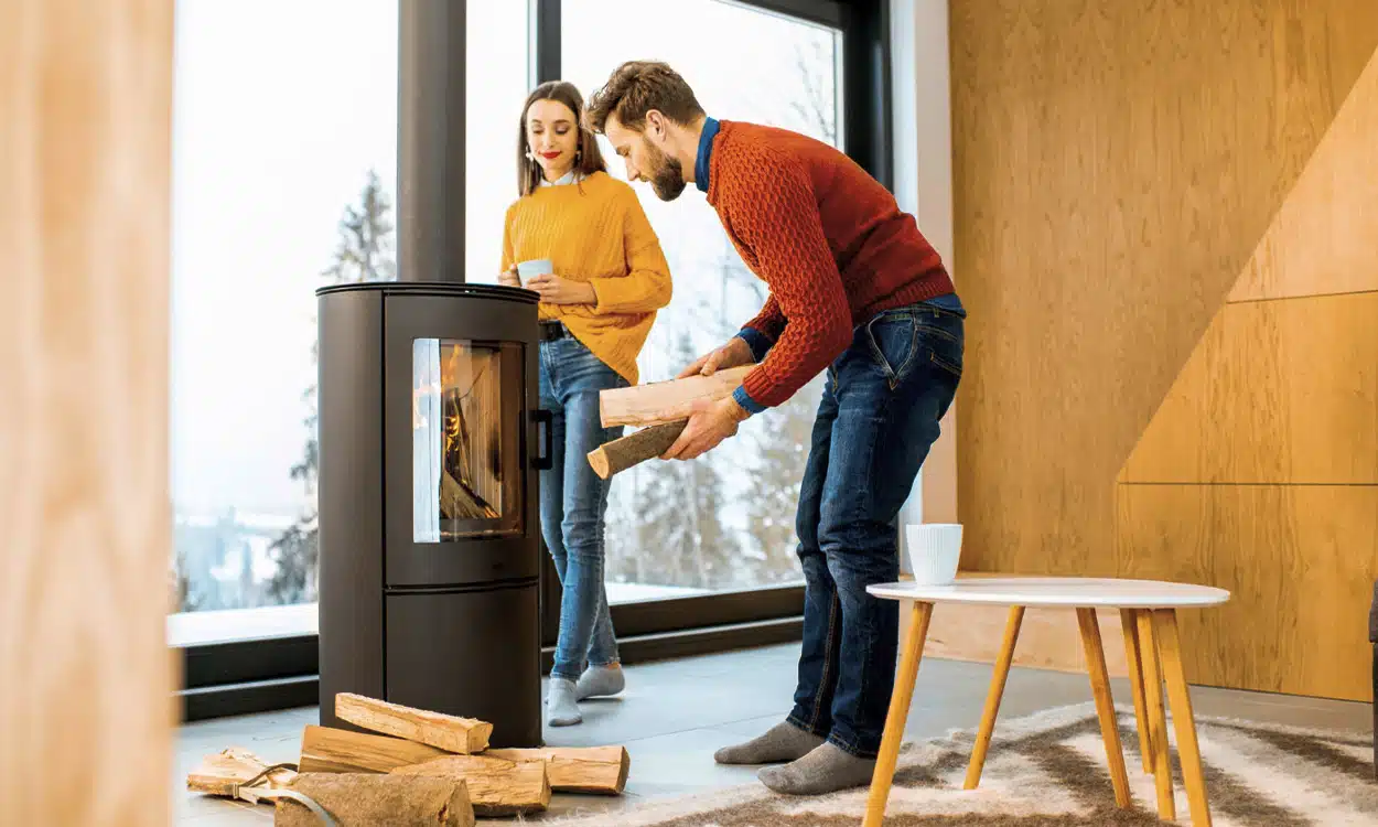 Couple qui rempli un poêle à bois avec des bûches de bois