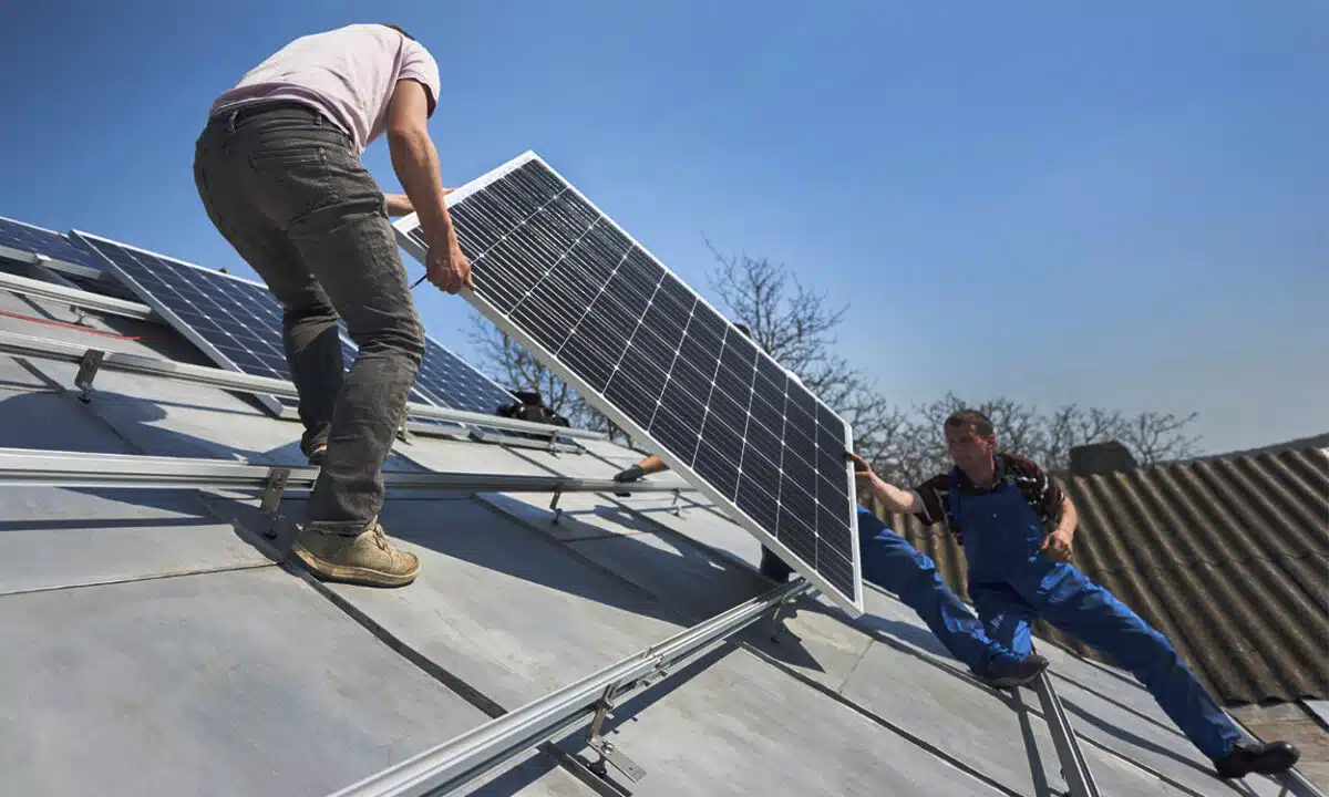 Des ouvriers qui installent des panneaux solaires sur un toit très pentu