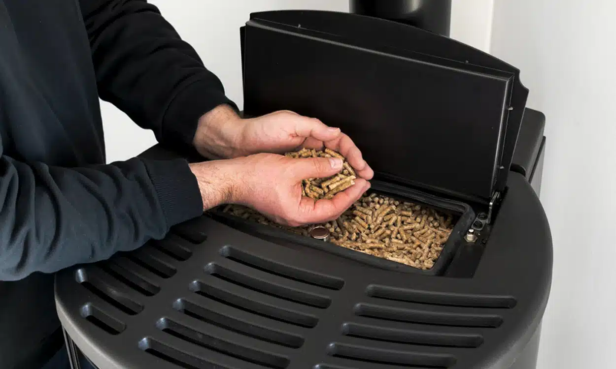 Un homme qui remplis de pellets son poêle à granules