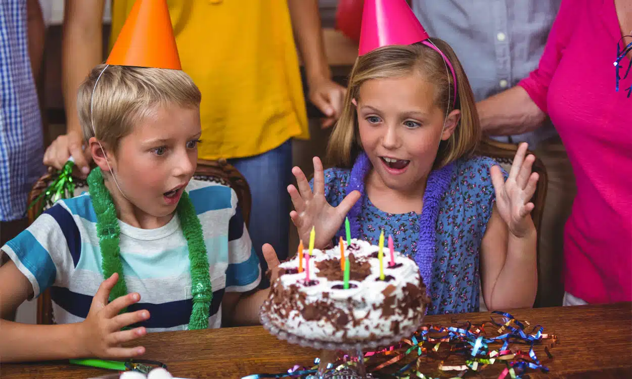 Une fille et un garçon fêtent leur anniversaire devant un gâteau