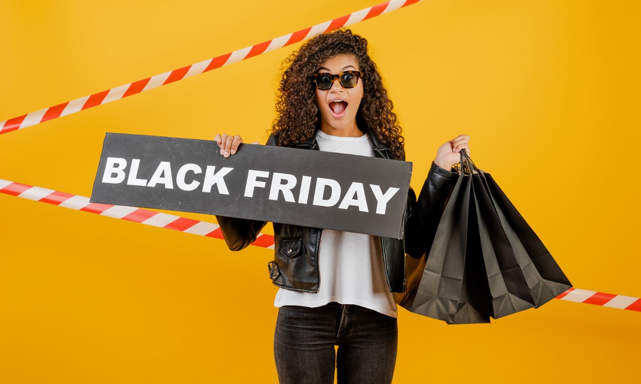 Une belle jeune femme africaine tenant des sacs shopping et une pancarte "Black Friday"