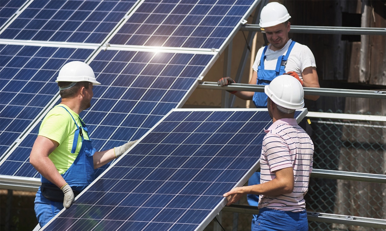 Une équipe de trois ouvriers installe des panneaux solaires photovoltaïques