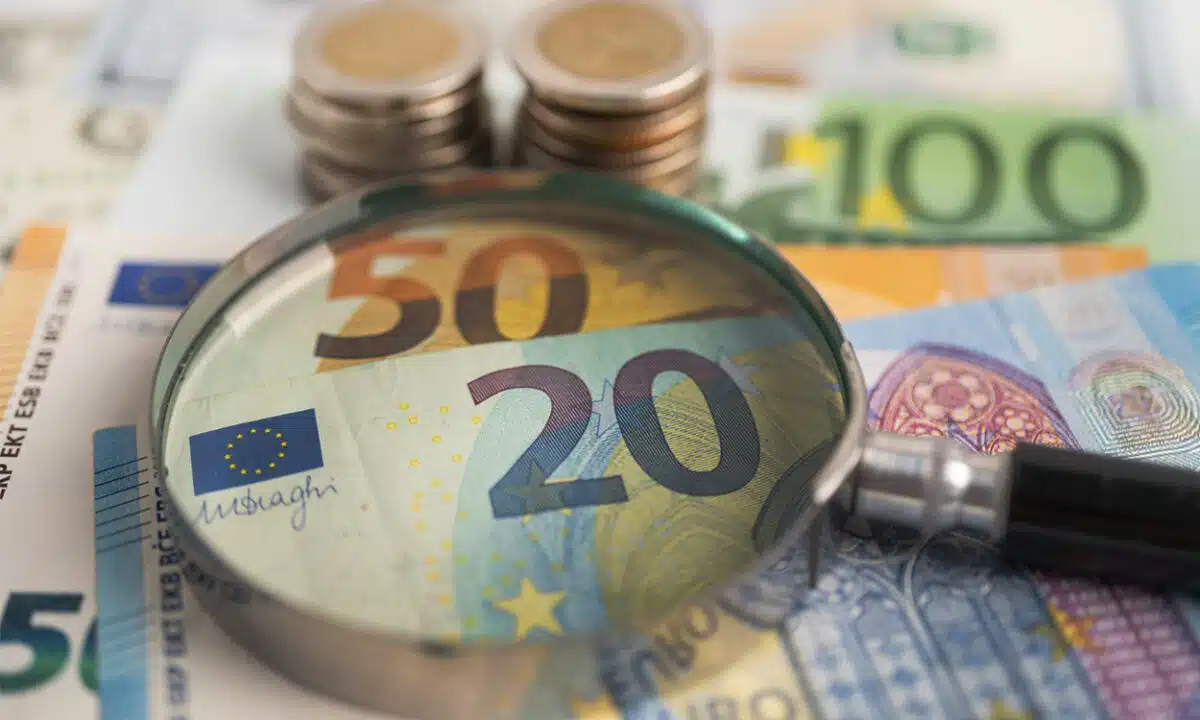Une loupe posée sur des billets de banque en euro