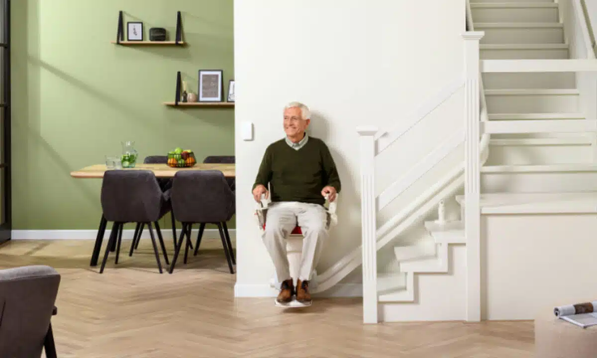Homme âgé assis sur un monte escaliers de marque otolift