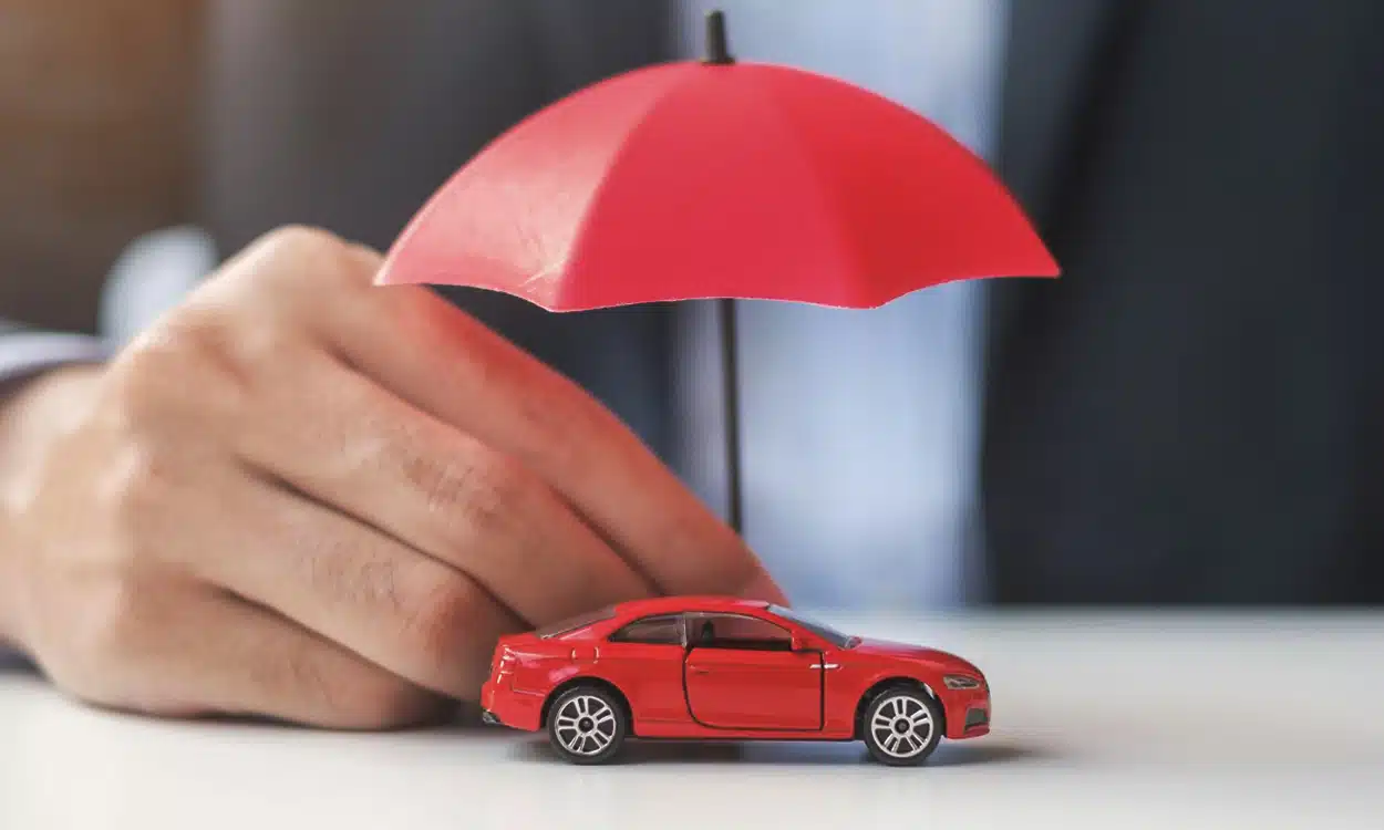 Une main qui tient en parapluie rouge pour protéger une voiture rouge