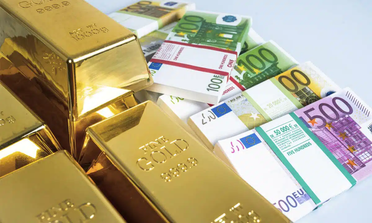Lingots d'or à côtés de liasses de grosses coupures de billets en euro