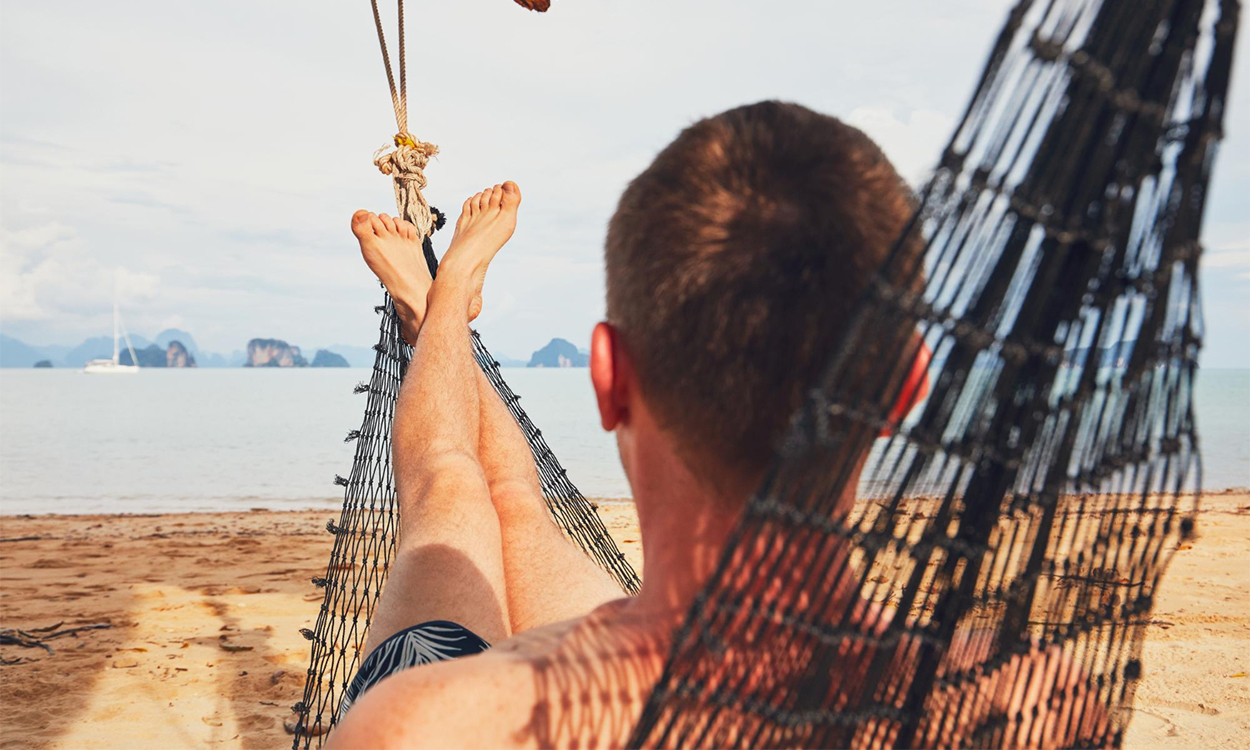 Jeune homme dans un hamac sur une plage paradisiaque